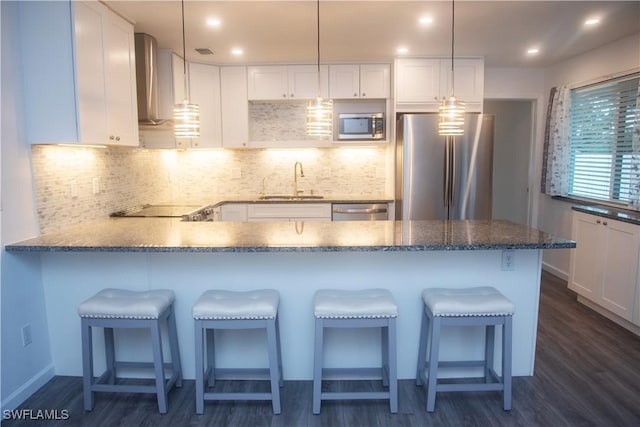 kitchen with pendant lighting, a kitchen breakfast bar, white cabinetry, and stainless steel appliances