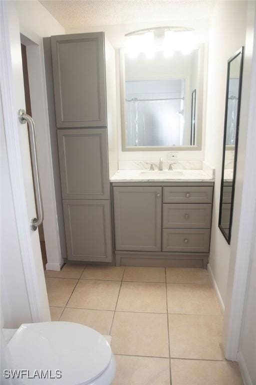 bathroom with toilet, vanity, and tile patterned flooring