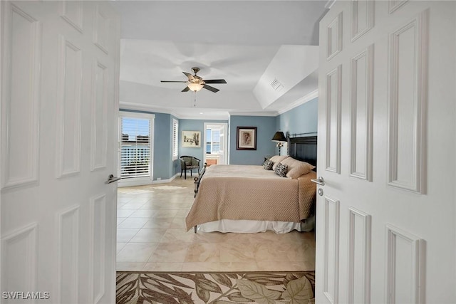 bedroom featuring ceiling fan, a raised ceiling, light tile patterned floors, and crown molding