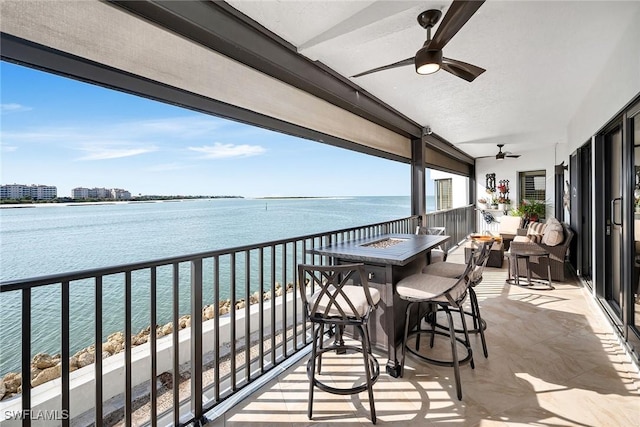 balcony with ceiling fan and a water view