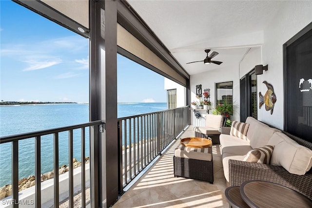 balcony with ceiling fan, a water view, and an outdoor living space