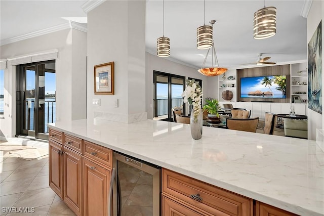 kitchen with light stone countertops, pendant lighting, built in features, and beverage cooler