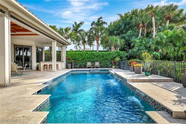 view of pool with pool water feature, an outdoor bar, and a patio