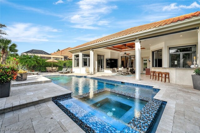 view of pool featuring ceiling fan, exterior bar, a patio, and an in ground hot tub