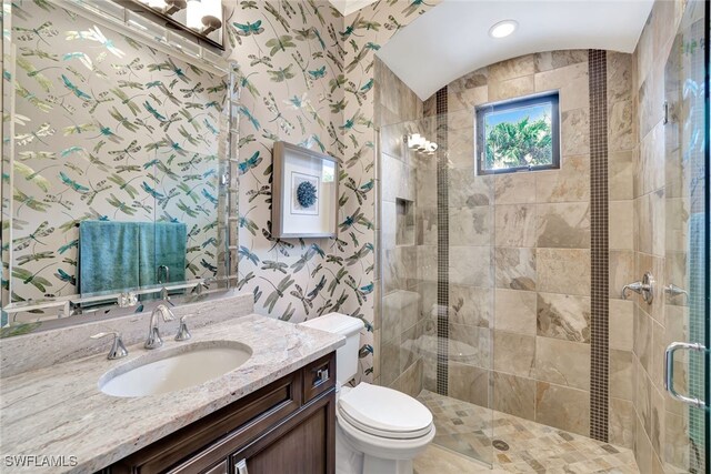 bathroom featuring toilet, a shower with shower door, and vanity