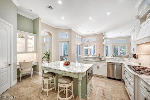 kitchen featuring a breakfast bar, stainless steel appliances, sink, a center island, and white cabinetry