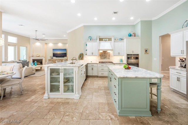 kitchen with sink, gas stovetop, a kitchen breakfast bar, premium range hood, and kitchen peninsula