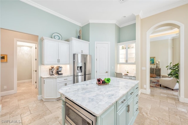 kitchen featuring a center island, stainless steel appliances, white cabinetry, and crown molding