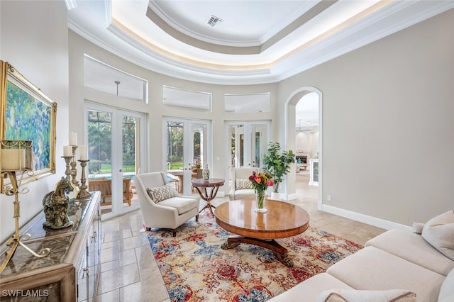 living room featuring a raised ceiling, a towering ceiling, ornamental molding, and french doors