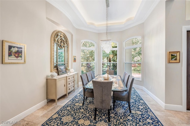 dining space with a raised ceiling, plenty of natural light, ornamental molding, and a notable chandelier