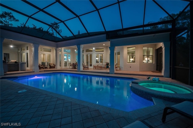 view of swimming pool featuring an in ground hot tub, a patio, a lanai, and exterior kitchen