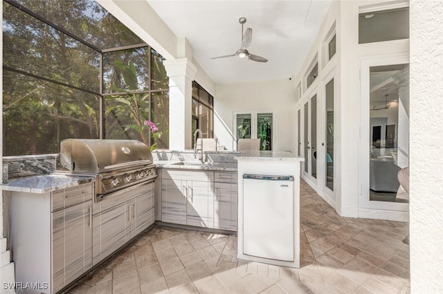 view of patio / terrace featuring ceiling fan, area for grilling, sink, and glass enclosure