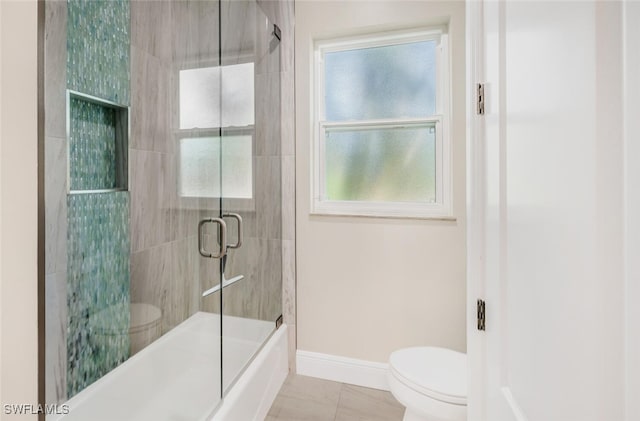 bathroom with tile patterned flooring, toilet, and bath / shower combo with glass door