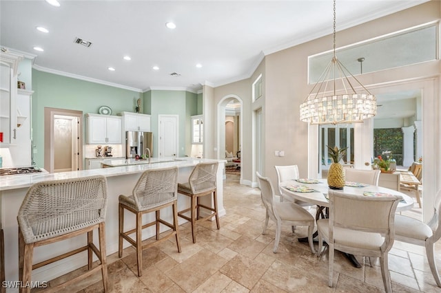 kitchen with stainless steel fridge, a kitchen breakfast bar, pendant lighting, white cabinets, and a chandelier