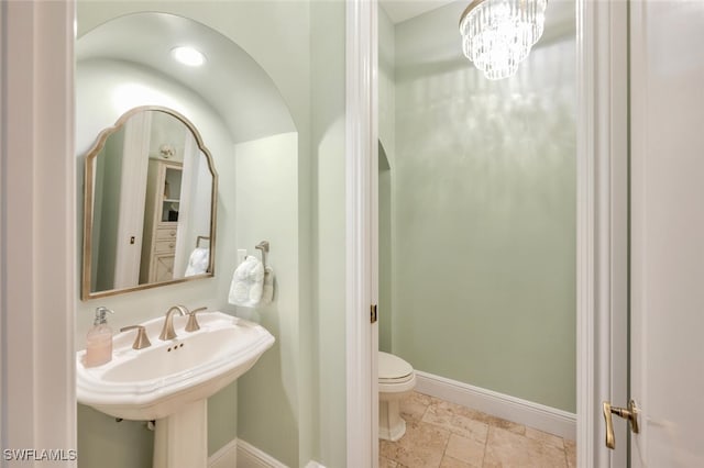 bathroom with an inviting chandelier, toilet, and sink