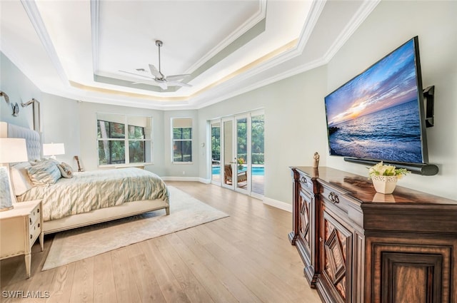 bedroom with ceiling fan, light hardwood / wood-style flooring, access to outside, a tray ceiling, and ornamental molding