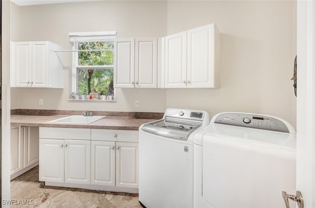 laundry area featuring cabinets, washer and dryer, and sink