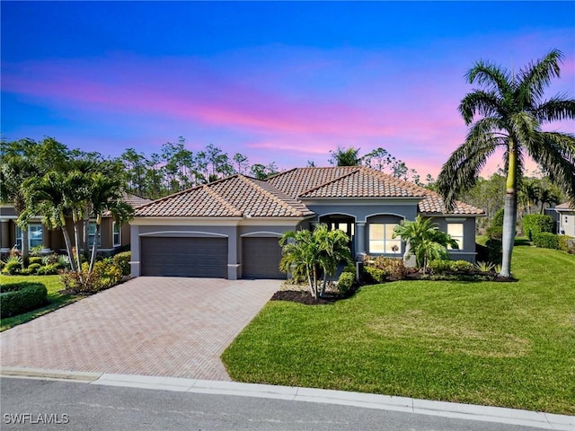 mediterranean / spanish-style home with a yard and a garage