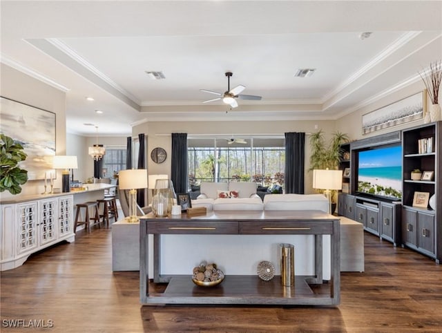 living room with dark wood-type flooring, crown molding, and a tray ceiling