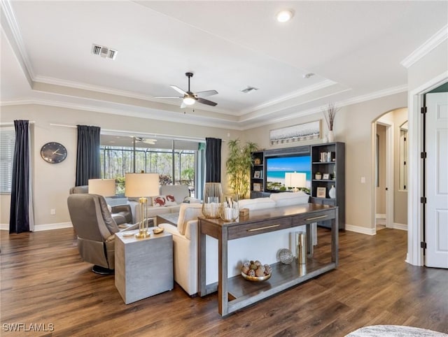 living room featuring a raised ceiling, ceiling fan, dark hardwood / wood-style floors, and ornamental molding