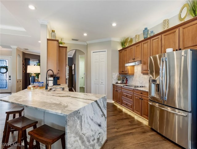 kitchen featuring kitchen peninsula, sink, crown molding, a breakfast bar area, and stainless steel fridge