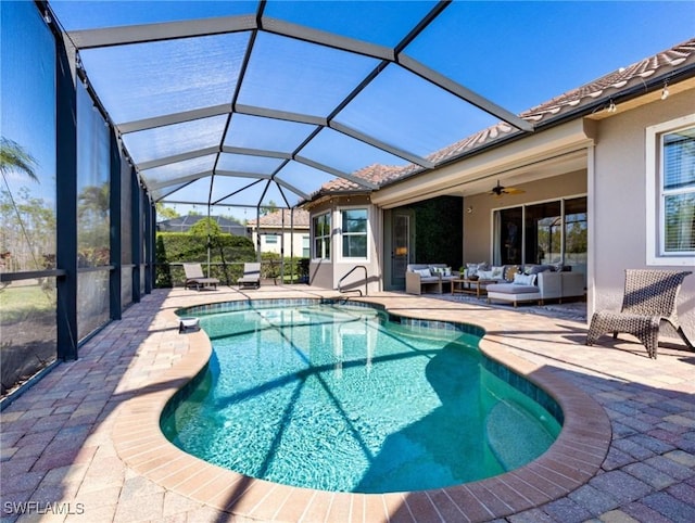 view of swimming pool with ceiling fan, an outdoor living space, a patio area, and glass enclosure