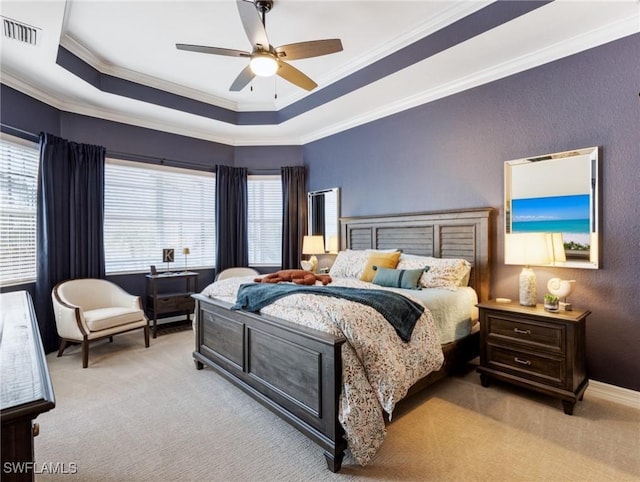 carpeted bedroom with ceiling fan, crown molding, and a tray ceiling