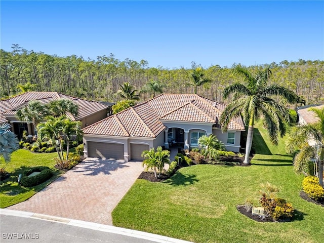 mediterranean / spanish home with a garage and a front lawn