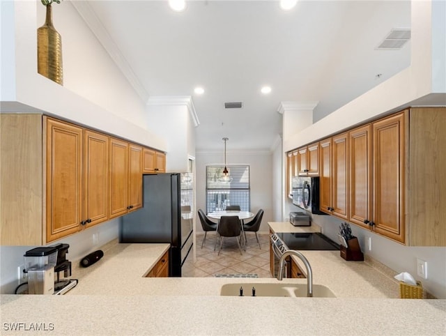 kitchen with pendant lighting, sink, crown molding, black refrigerator, and light tile patterned flooring