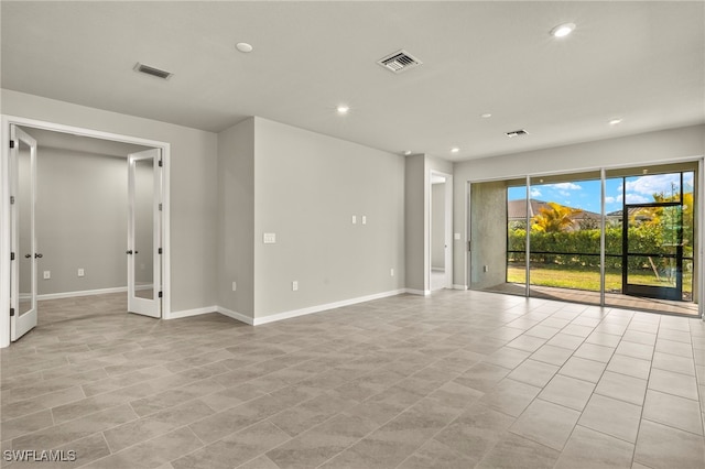 tiled spare room featuring french doors