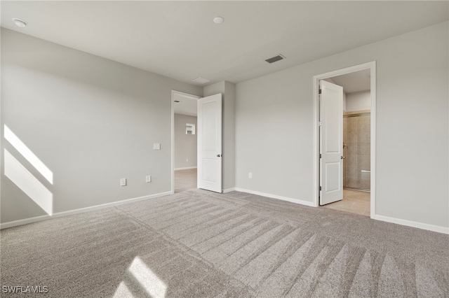 unfurnished bedroom featuring ensuite bath and light colored carpet