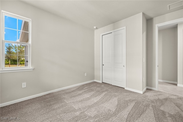 unfurnished bedroom with light carpet and a closet