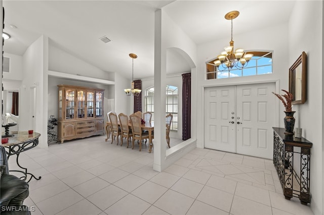 tiled foyer with high vaulted ceiling and a chandelier