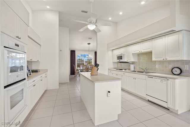 kitchen with white appliances, pendant lighting, and white cabinetry