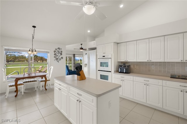 kitchen with white appliances, white cabinets, decorative light fixtures, and a center island