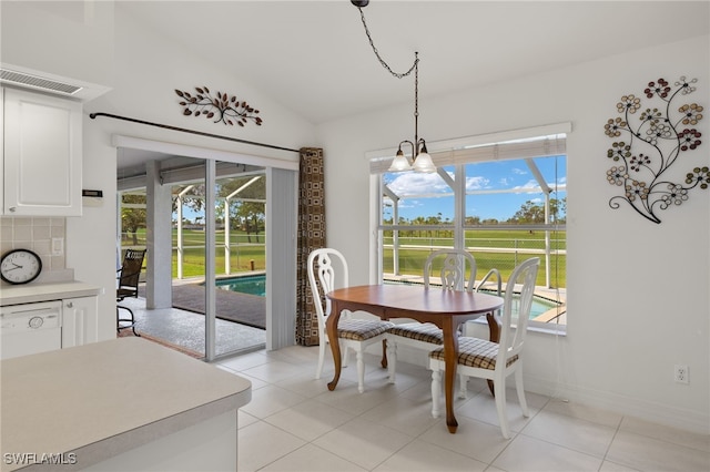 dining area with lofted ceiling, a notable chandelier, and light tile patterned floors