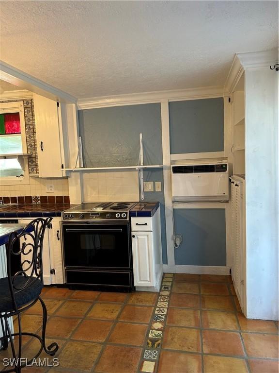 kitchen featuring white cabinets, black electric range, dark tile patterned flooring, decorative backsplash, and crown molding