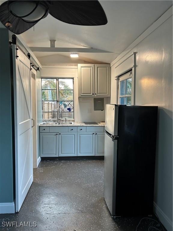 kitchen with sink, a barn door, and stainless steel fridge