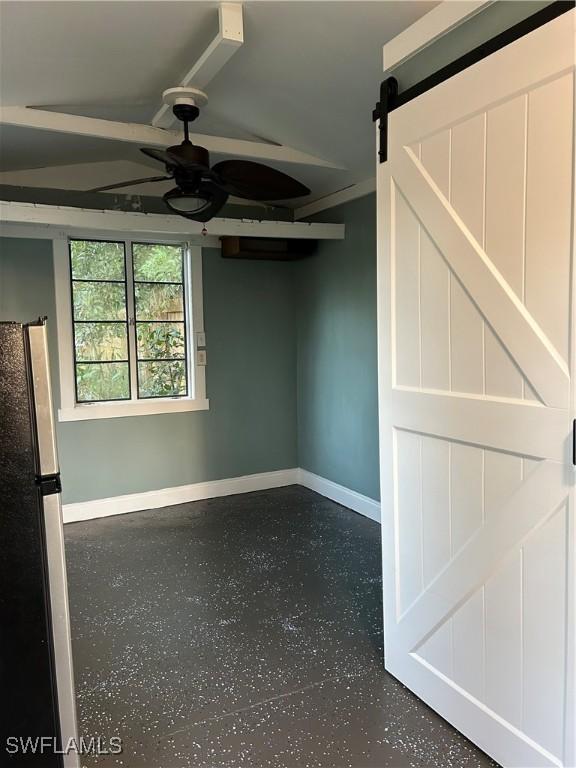 spare room with ceiling fan and a barn door