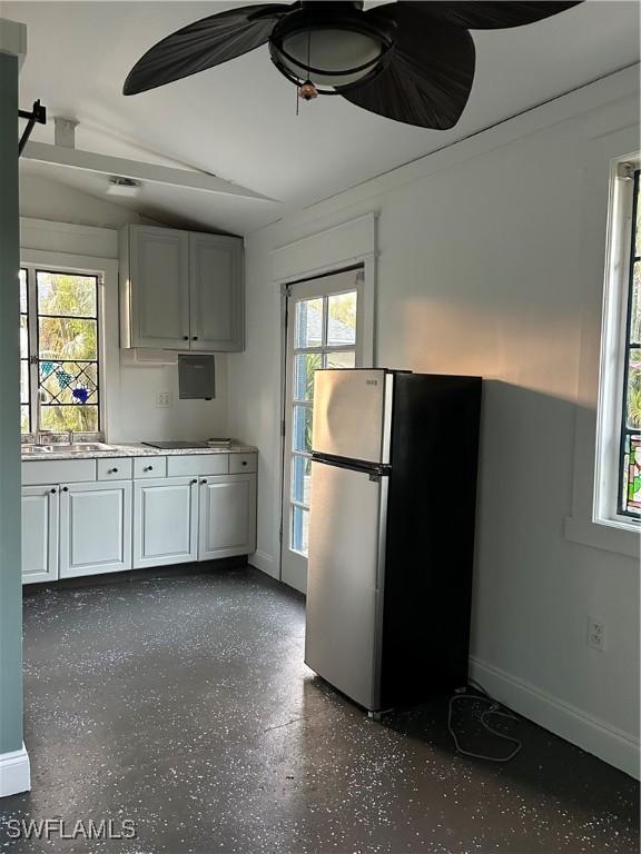 kitchen featuring sink, white cabinetry, ceiling fan, stainless steel fridge, and black electric stovetop