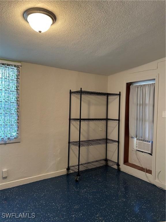 unfurnished room featuring a textured ceiling and cooling unit