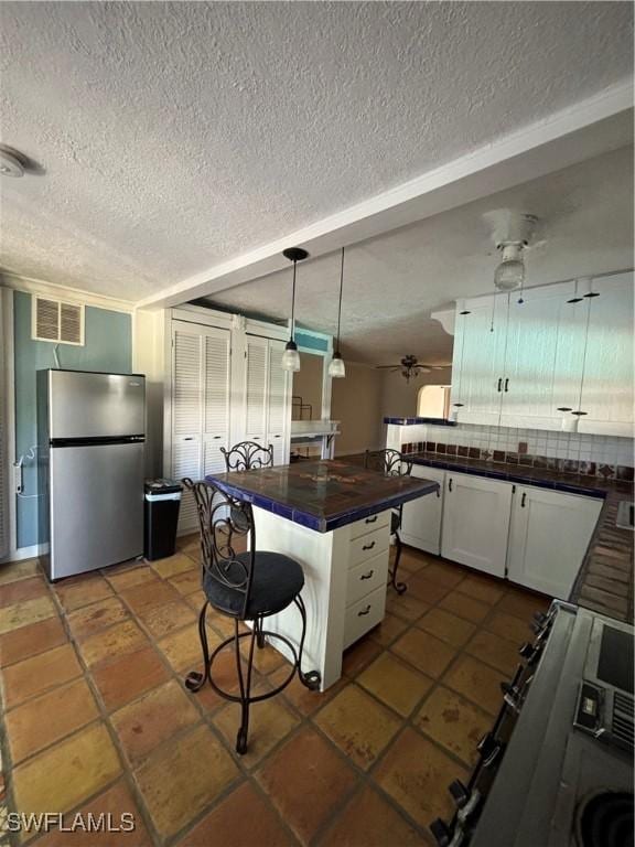 kitchen featuring white cabinetry, hanging light fixtures, a breakfast bar area, appliances with stainless steel finishes, and ceiling fan