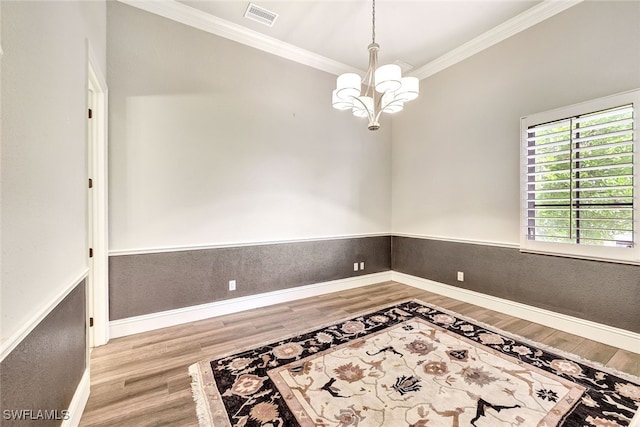 unfurnished room featuring ornamental molding, hardwood / wood-style floors, and a notable chandelier