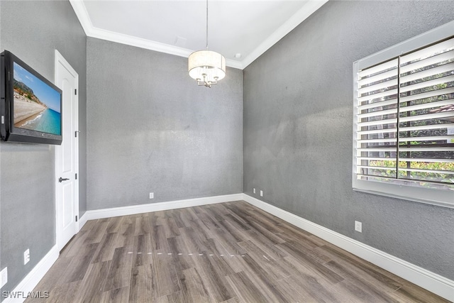 spare room with ornamental molding, hardwood / wood-style floors, and an inviting chandelier