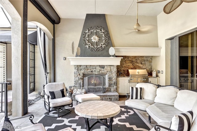 living room with ceiling fan, a stone fireplace, and sink