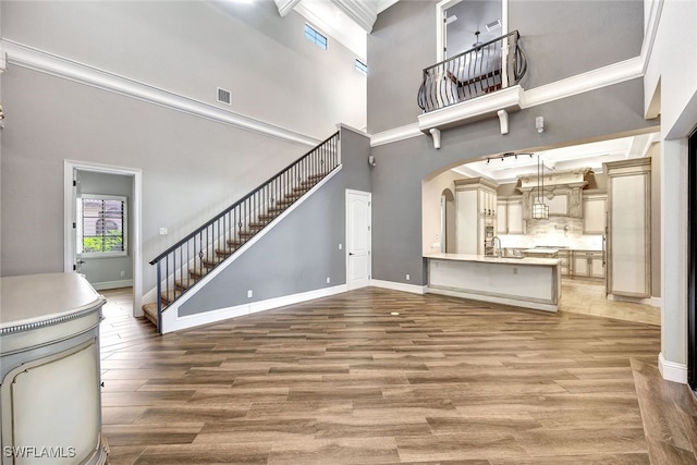 unfurnished living room with crown molding, a high ceiling, and hardwood / wood-style flooring