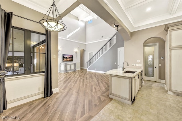 kitchen with beamed ceiling, sink, hanging light fixtures, crown molding, and light stone countertops