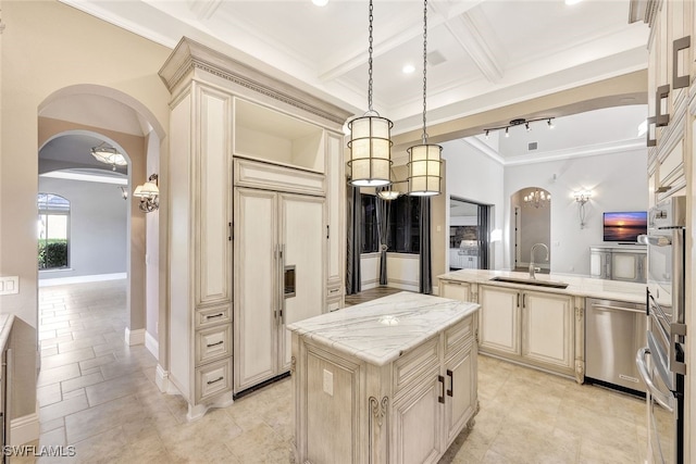 kitchen featuring sink, appliances with stainless steel finishes, a center island, decorative light fixtures, and cream cabinetry