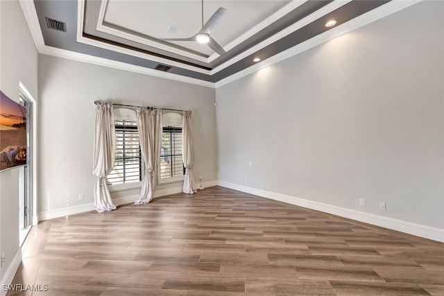 spare room with hardwood / wood-style floors, a tray ceiling, and ornamental molding