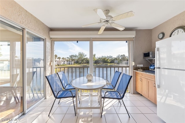 sunroom / solarium featuring ceiling fan and a water view